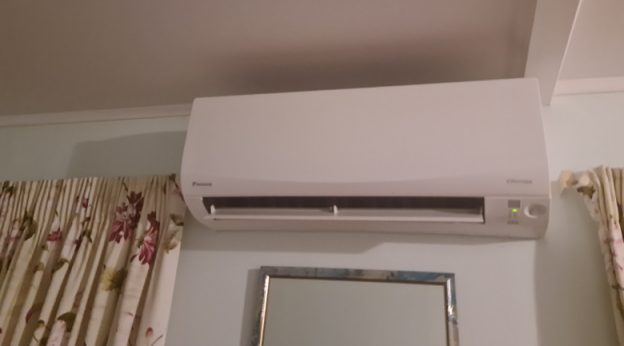 Wall-mounted ductless mini split indoor unit installed high on a bedroom wall