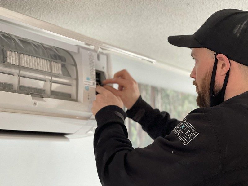 Technician adjusting a wall-mounted mini split indoor unit during installation